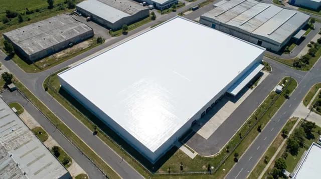 Toiture d'entrepôt industriel traitée par un revêtement réfléchissant blanc, vue aérienne